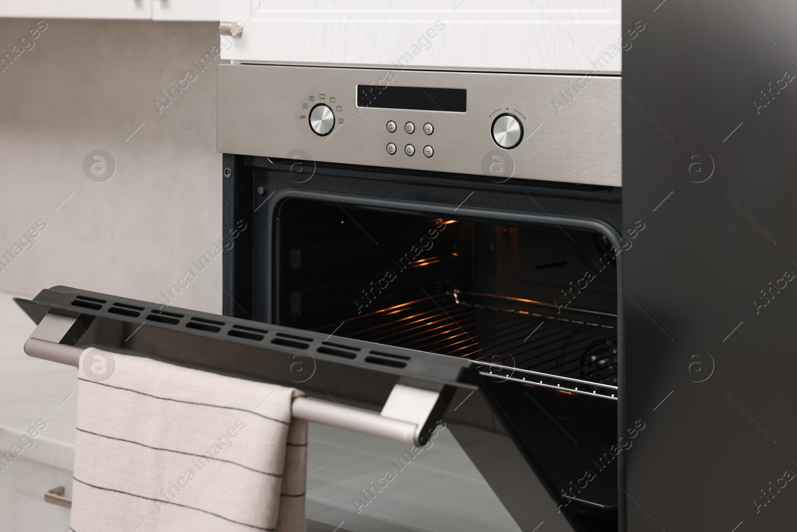 Photo of Open electric oven with towel in kitchen. Cooking appliance