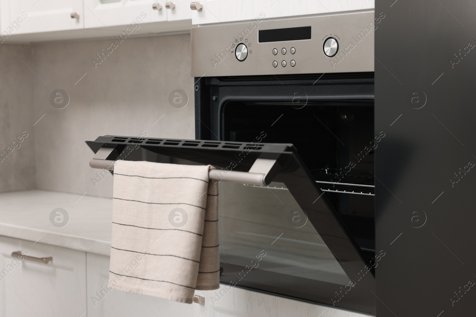 Photo of Open electric oven with towel in kitchen. Cooking appliance