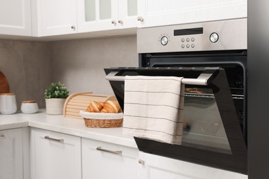 Photo of Open electric oven with towel in kitchen. Cooking appliance