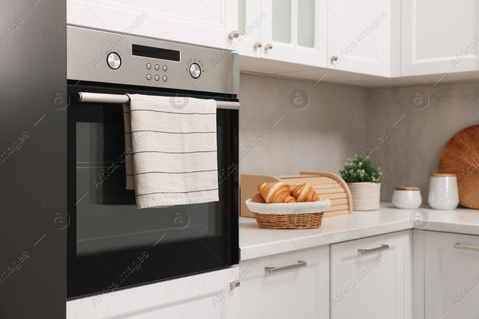 Photo of Electric oven with towel in kitchen. Cooking appliance