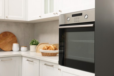 Photo of Electric oven and croissants in kitchen. Cooking appliance