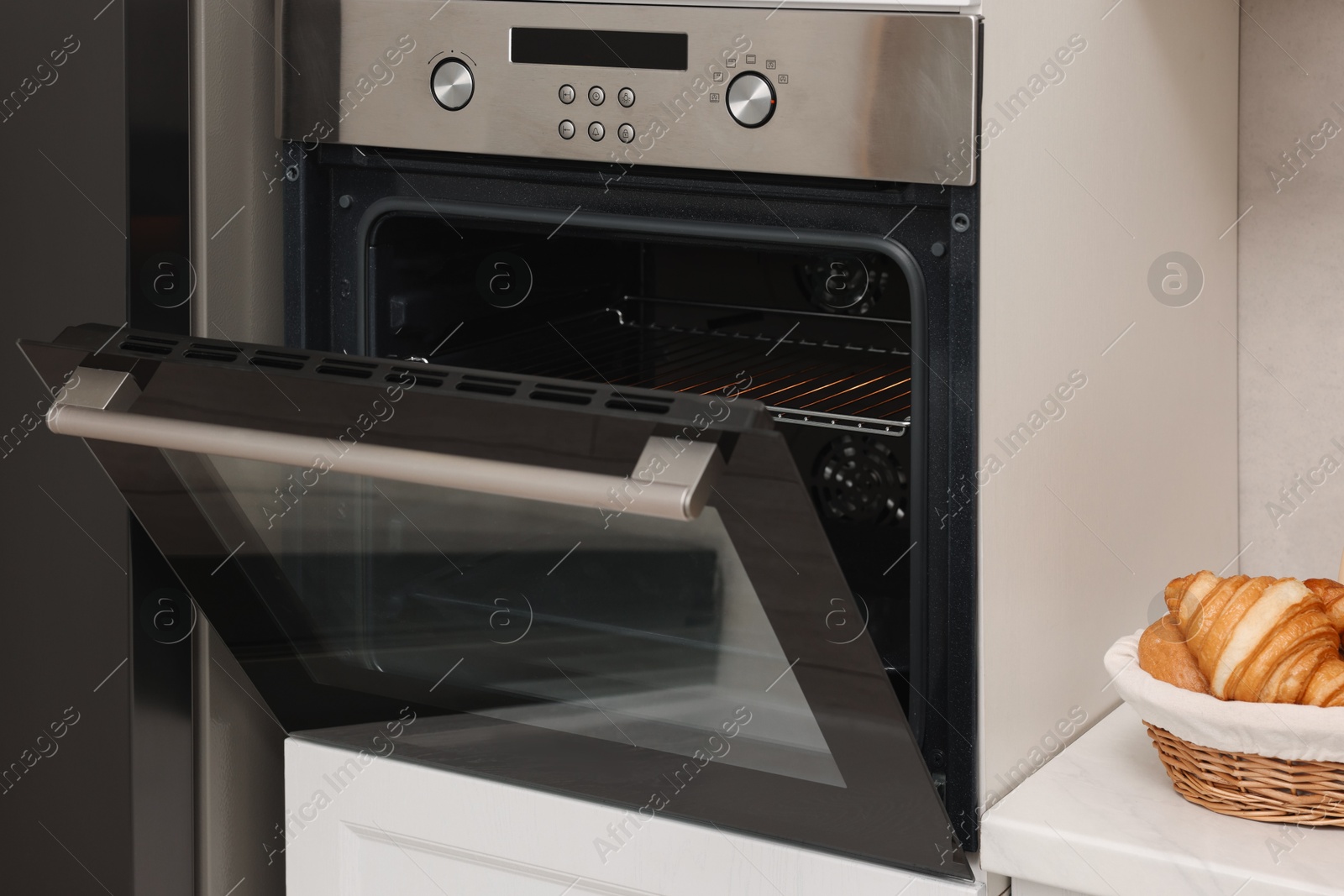 Photo of Open electric oven and croissants in kitchen. Cooking appliance