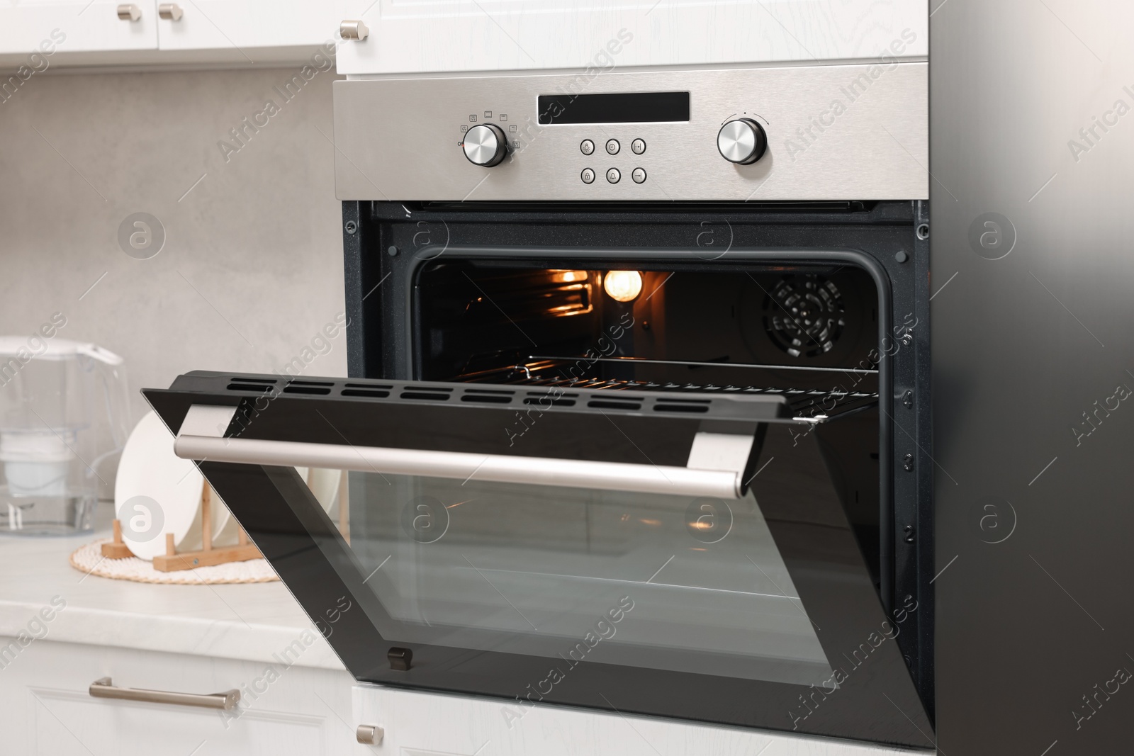 Photo of Open electric oven with towel in kitchen. Cooking appliance