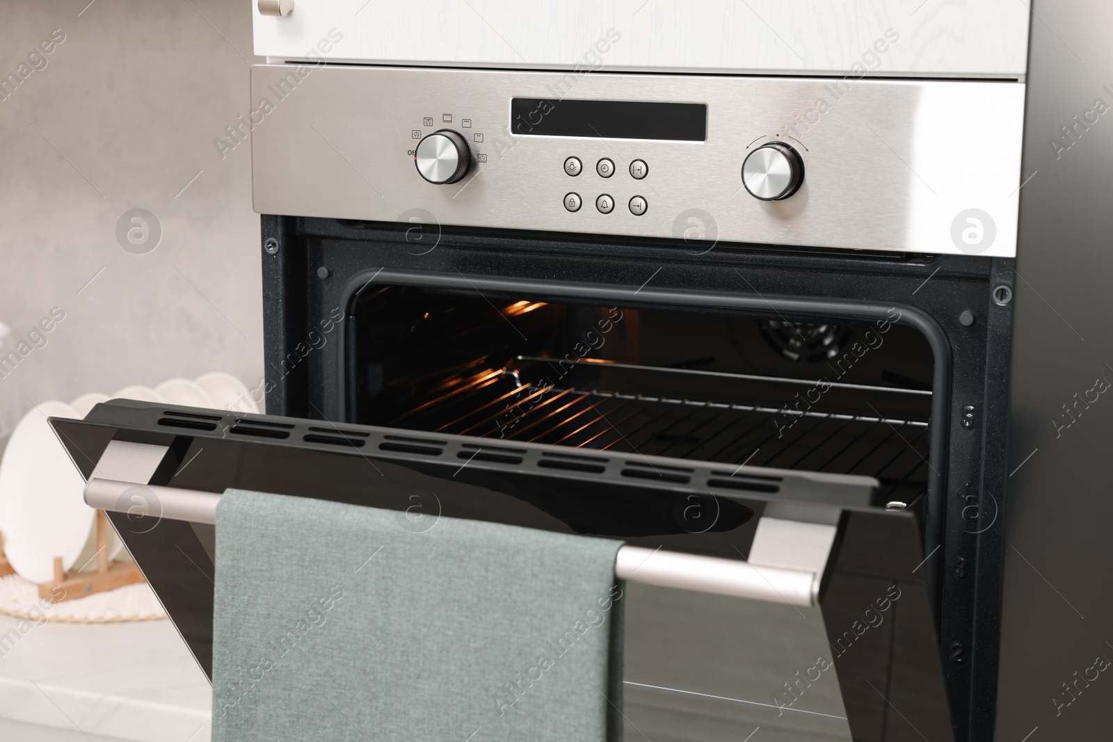 Photo of Open electric oven with towel in kitchen. Cooking appliance