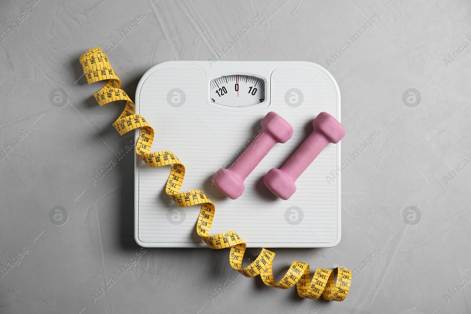 Photo of Bathroom scale, measuring tape and dumbbells on grey textured background, flat lay