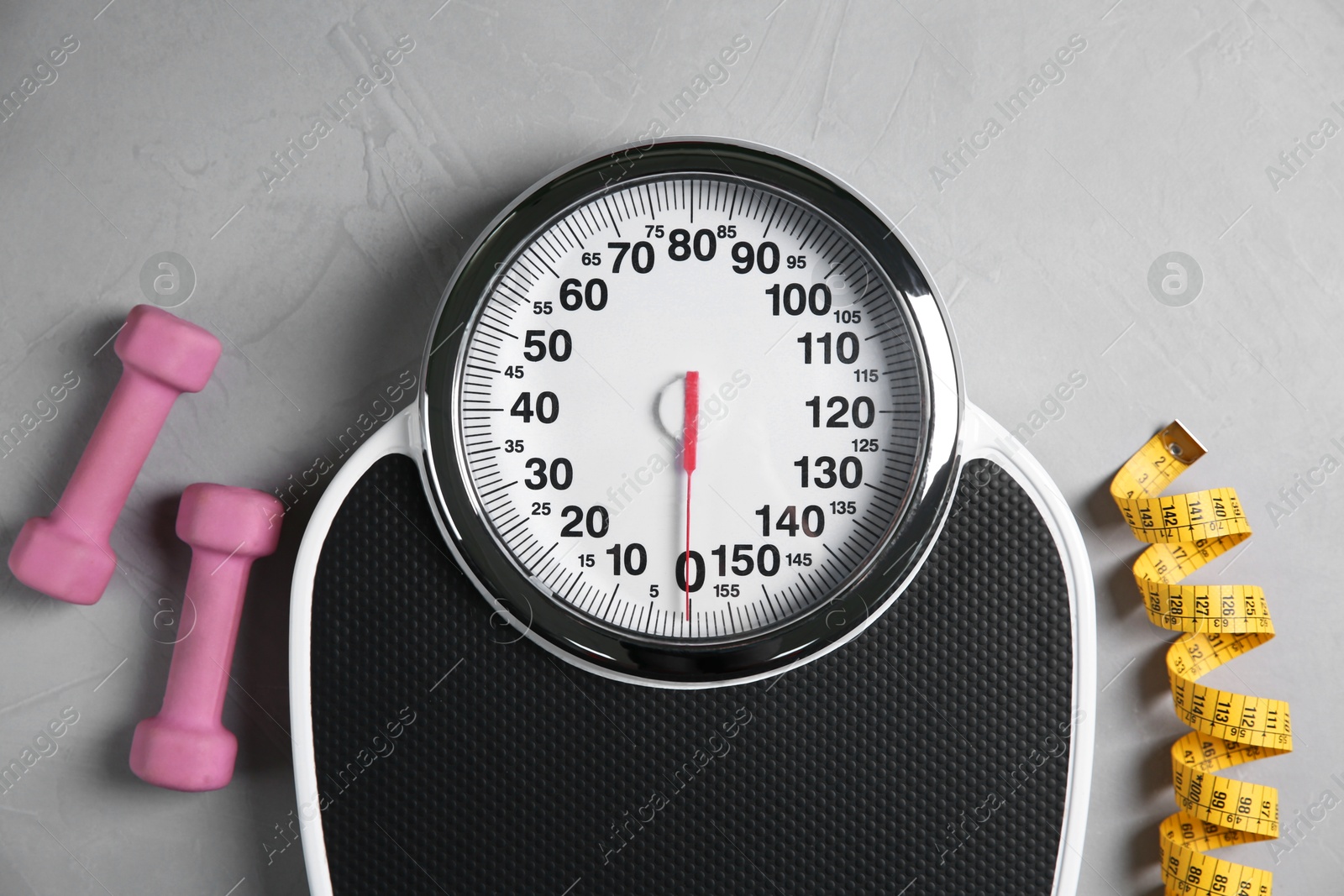 Photo of Bathroom scale, measuring tape and dumbbells on grey textured background, flat lay