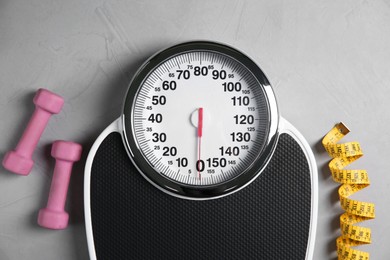 Photo of Bathroom scale, measuring tape and dumbbells on grey textured background, flat lay