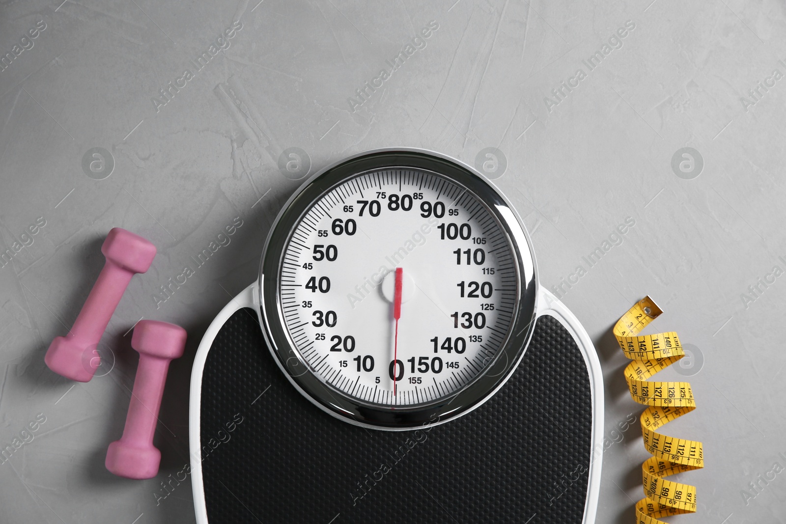 Photo of Bathroom scale, measuring tape and dumbbells on grey textured background, flat lay