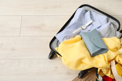 Photo of Open suitcase with traveler's belongings on floor, top view. Space for text