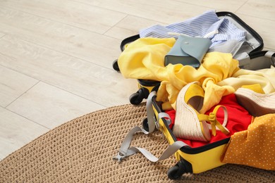 Photo of Open suitcase with traveler's belongings on floor, space for text