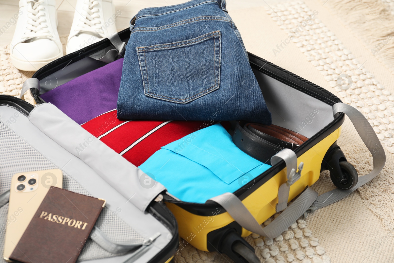 Photo of Open suitcase with traveler's belongings on floor, closeup