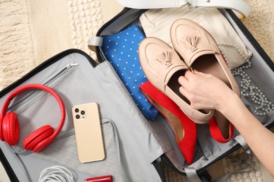 Woman packing suitcase for trip at home, top view