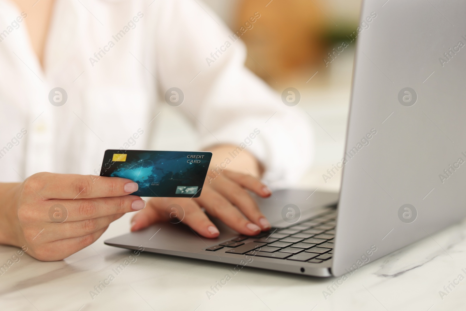 Photo of Online banking. Woman with credit card and laptop paying purchase at white marble table, closeup