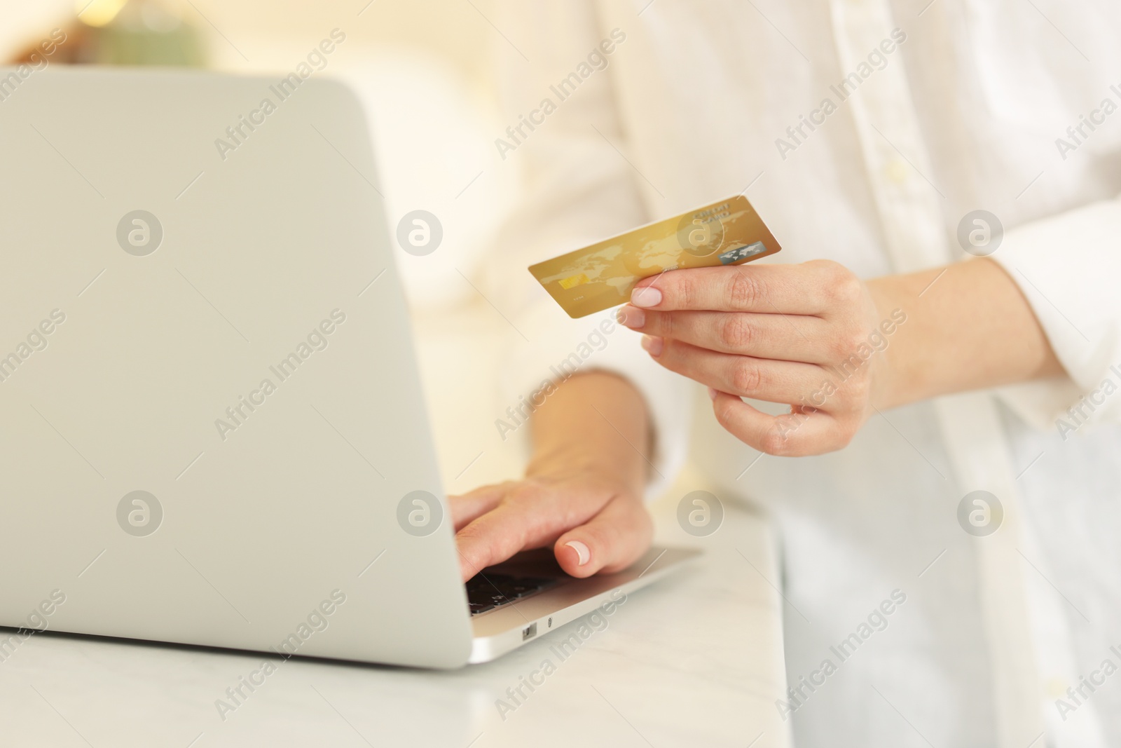 Photo of Online banking. Woman with credit card and laptop paying purchase at white table, closeup