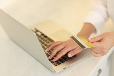 Photo of Online banking. Woman with credit card and laptop paying purchase at white table, closeup