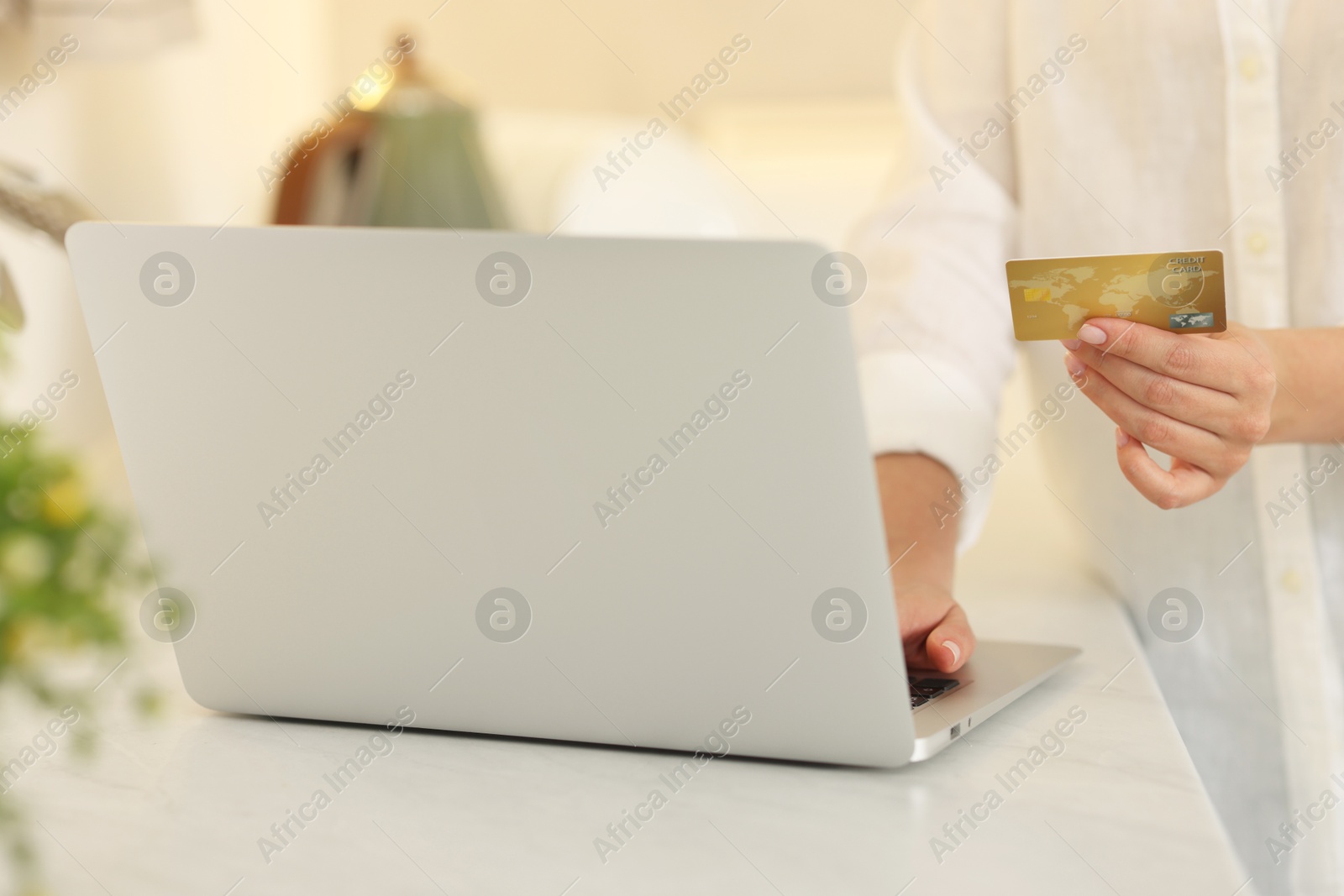 Photo of Online banking. Woman with credit card and laptop paying purchase at white table, closeup