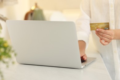 Photo of Online banking. Woman with credit card and laptop paying purchase at white table, closeup