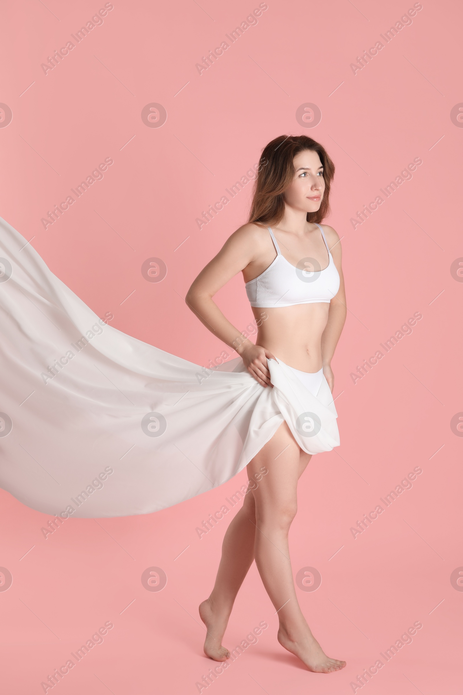 Photo of Woman covering her slim body with silk fabric against pink background