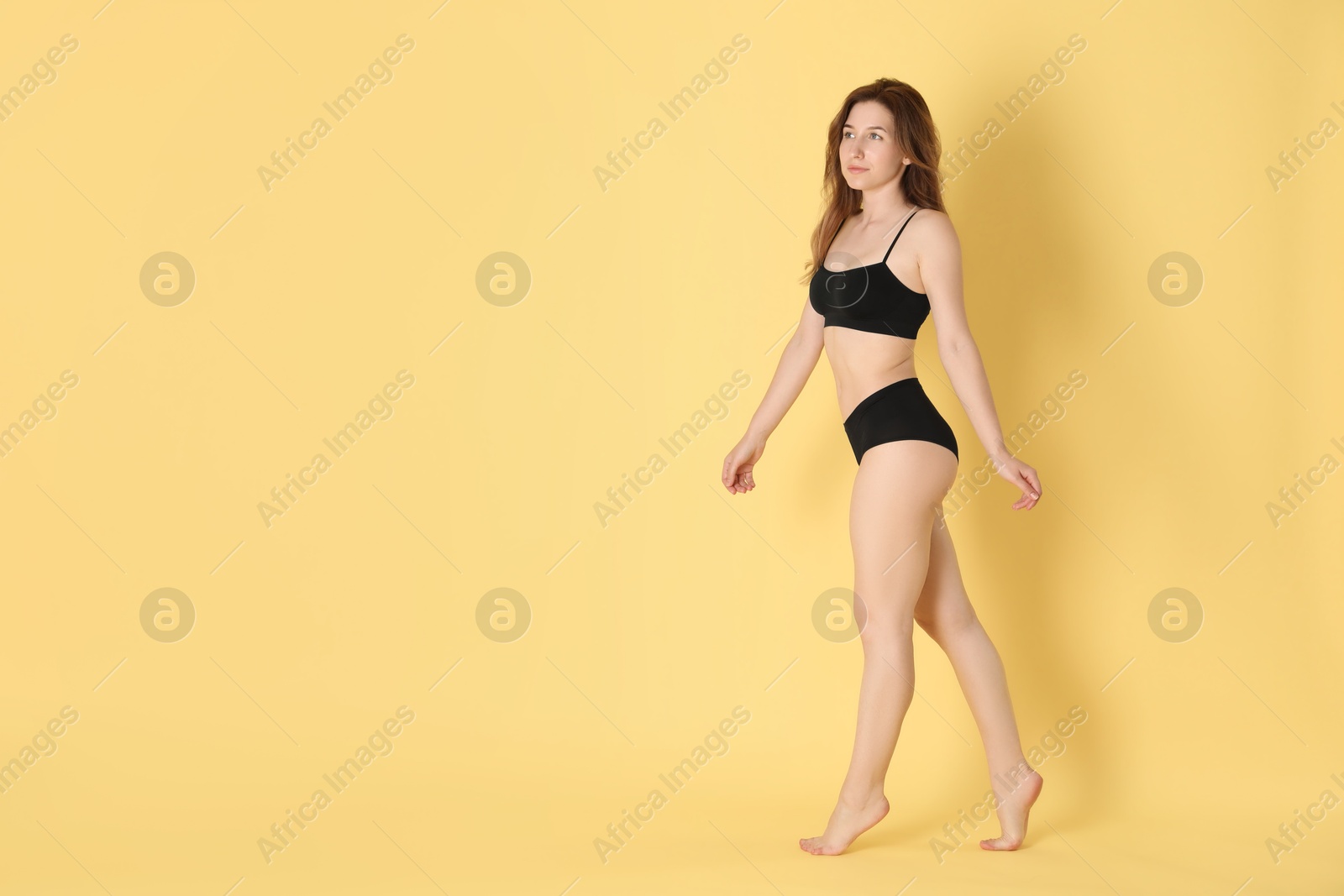 Photo of Woman with slim body posing on yellow background, space for text