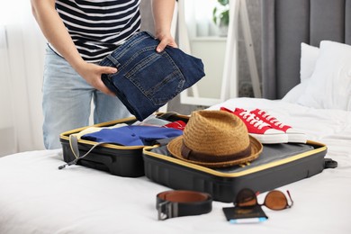 Man packing suitcase for trip in bedroom, closeup