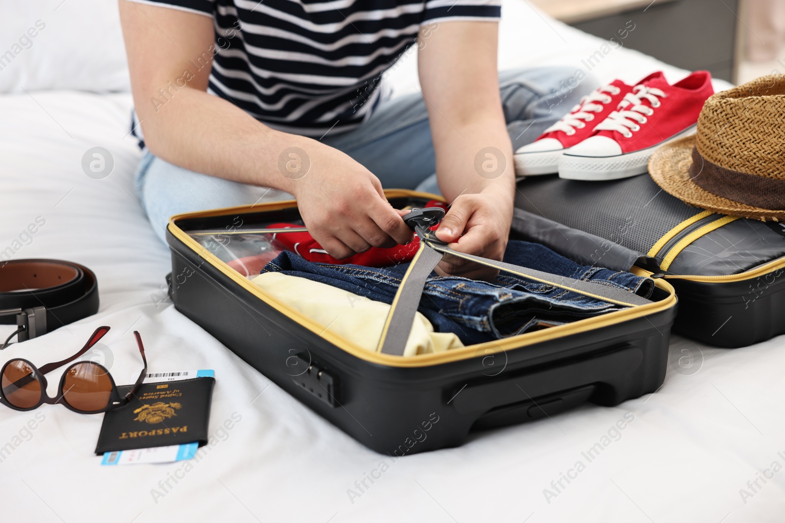 Photo of Man packing suitcase for trip in bedroom, closeup