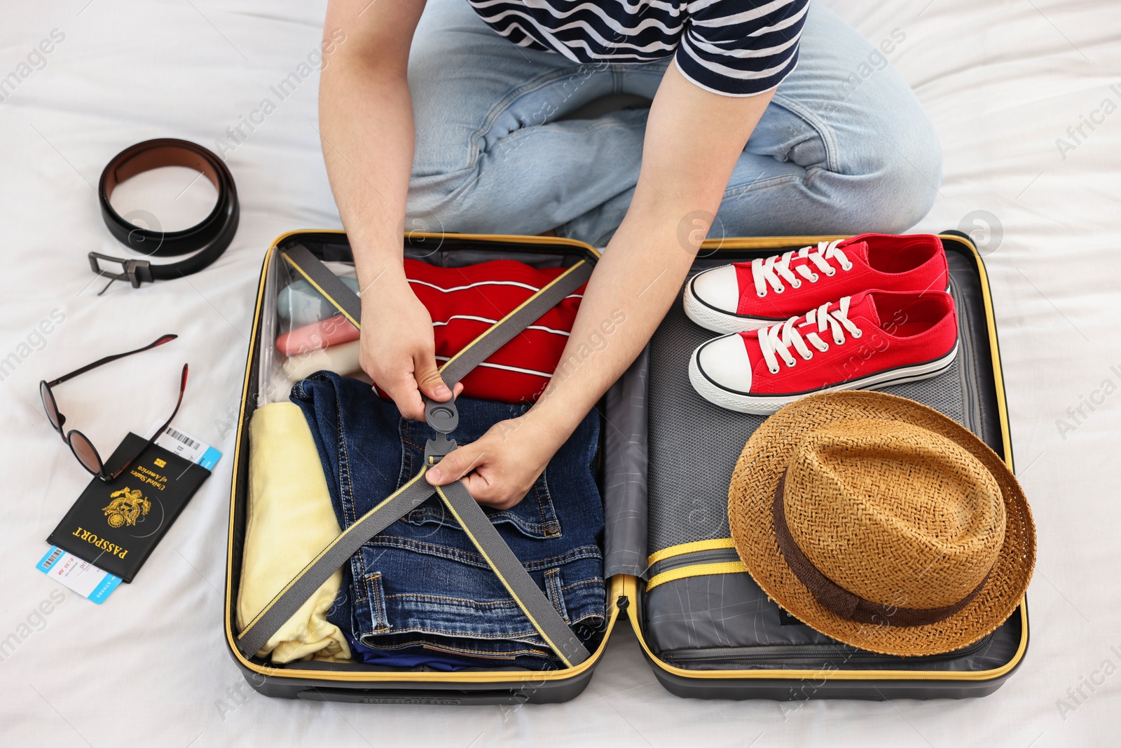 Photo of Man packing suitcase for trip on bed, closeup