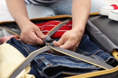 Man packing suitcase for trip indoors, closeup