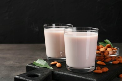 Glasses of almond milk and almonds on grey table