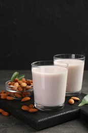 Glasses of almond milk and almonds on grey table