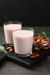 Glasses of almond milk and almonds on grey table