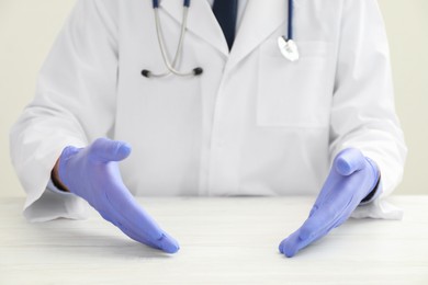 Photo of Doctor in gloves holding something at white table, selective focus