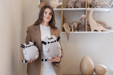 Photo of Woman with cute handmade toy cats in workshop