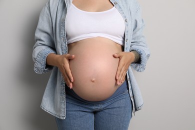 Photo of Pregnant woman on gray background, closeup view