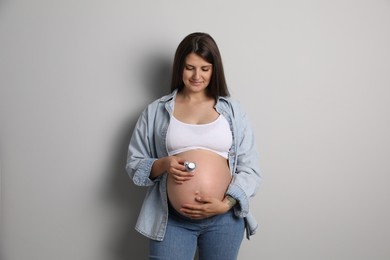 Photo of Pregnant woman with pacifier on gray background