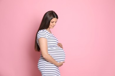 Beautiful pregnant woman on pink background, space for text