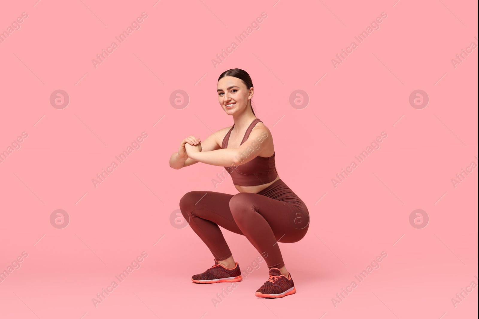 Photo of Young woman doing aerobic exercise on pink background