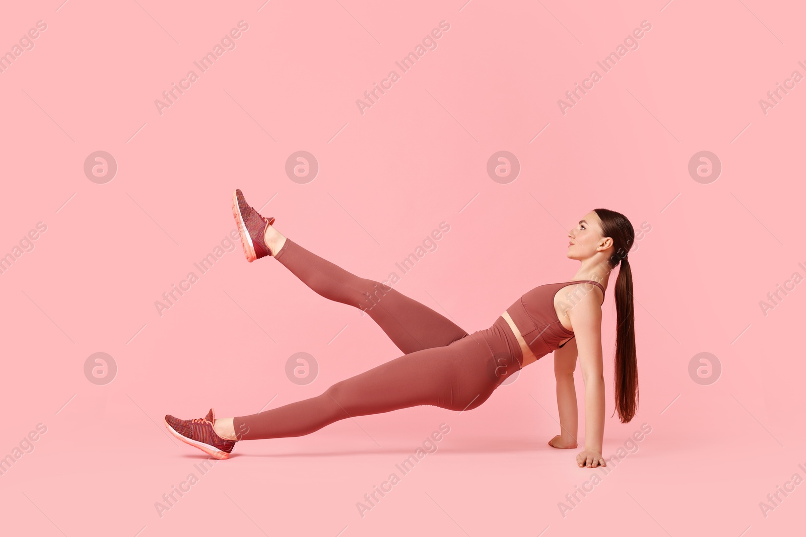 Photo of Young woman doing aerobic exercise on pink background