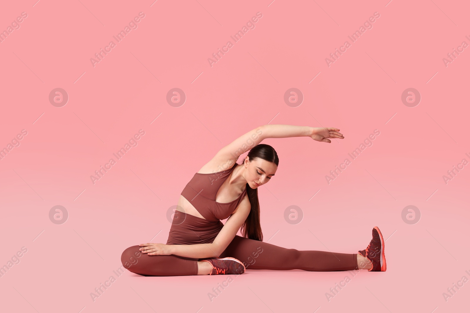 Photo of Aerobics. Young woman doing stretching exercise on pink background