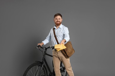 Photo of Postman with bicycle delivering letters on grey background