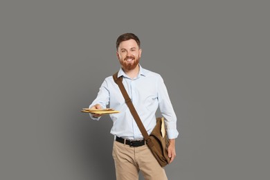Photo of Postman with brown bag delivering letters on grey background