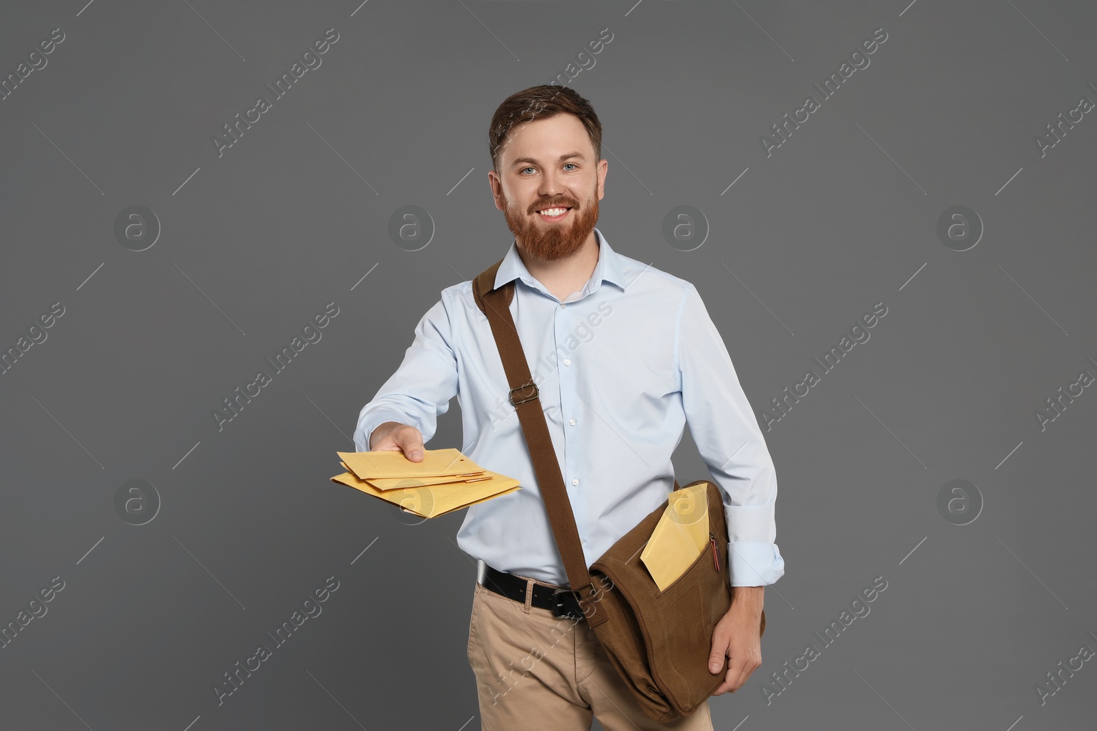 Photo of Postman with brown bag delivering letters on grey background