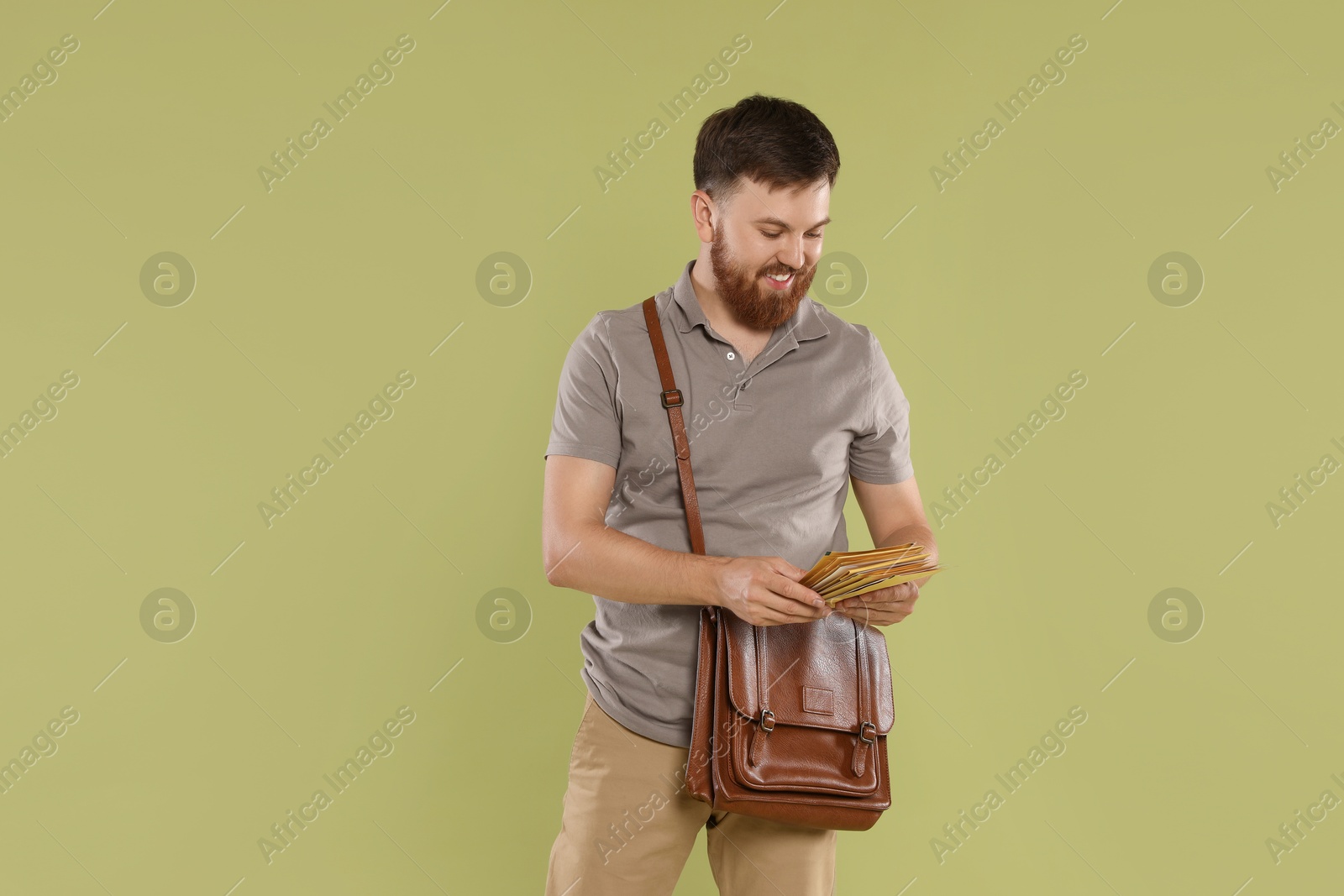 Photo of Postman with brown bag delivering letters on light green background