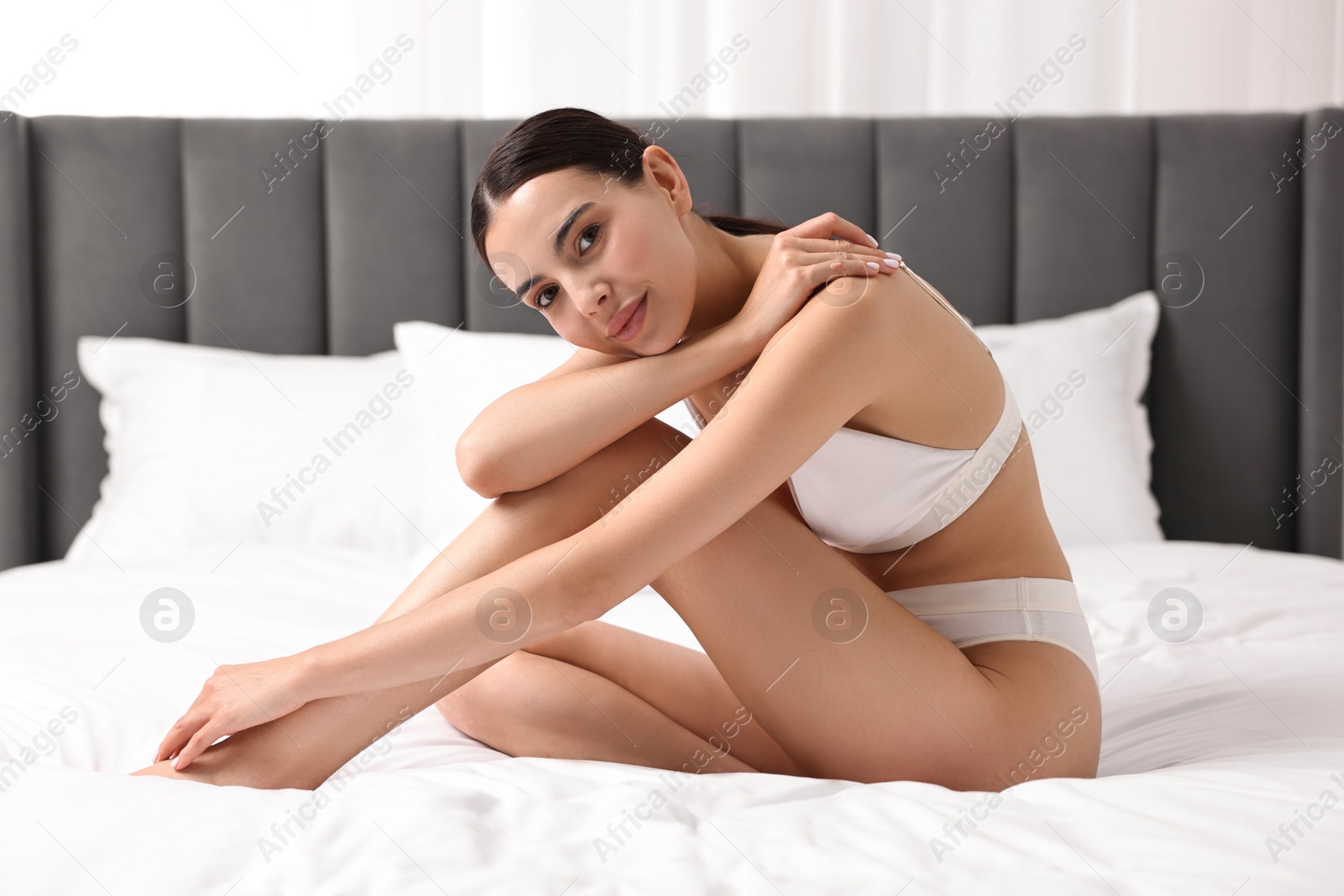 Photo of Beautiful woman with perfect skin in underwear on bed. Body care