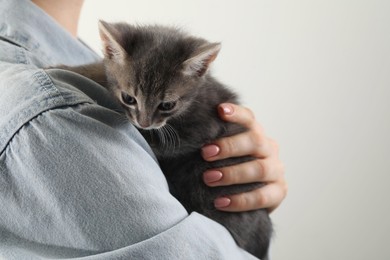 Photo of Woman with cute fluffy kitten on grey background, closeup. Space for text