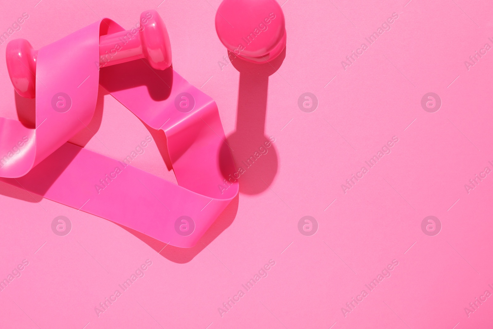 Photo of Dumbbells and fitness elastic band on pink background, flat lay. Space for text