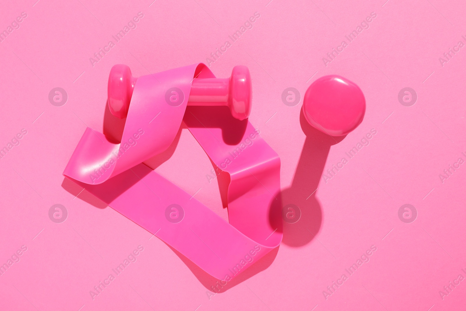 Photo of Dumbbells and fitness elastic band on pink background, flat lay