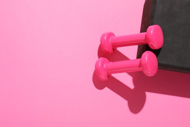 Photo of Dumbbells and yoga block on pink background, flat lay. Space for text