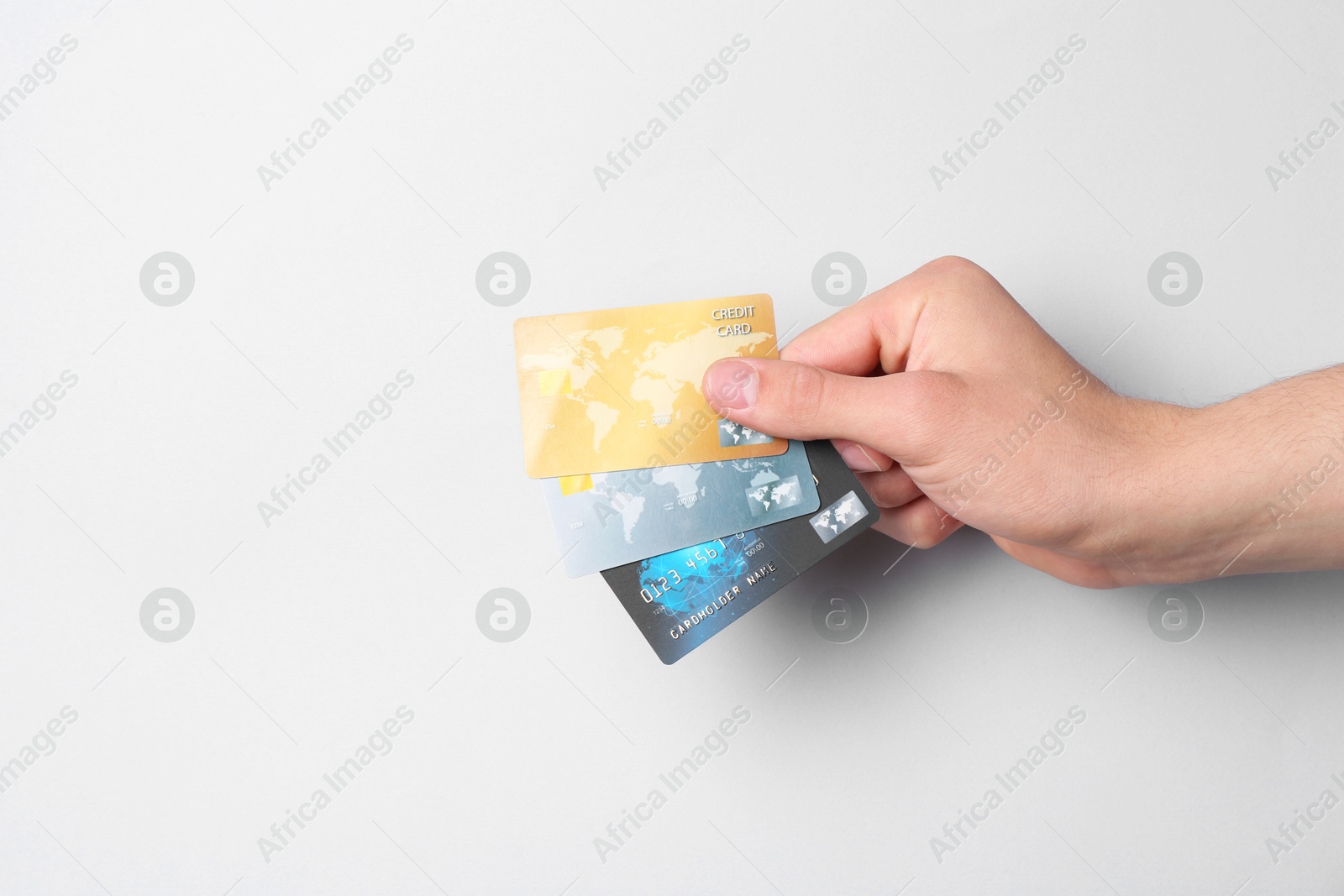 Photo of Man holding credit cards on light grey background, closeup