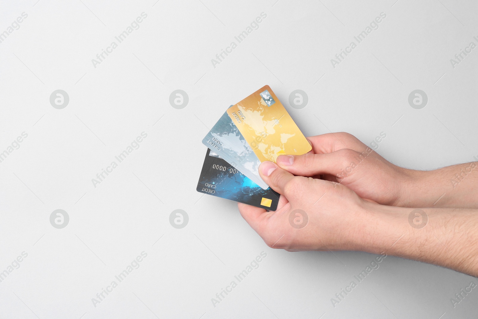 Photo of Man holding credit cards on light grey background, closeup