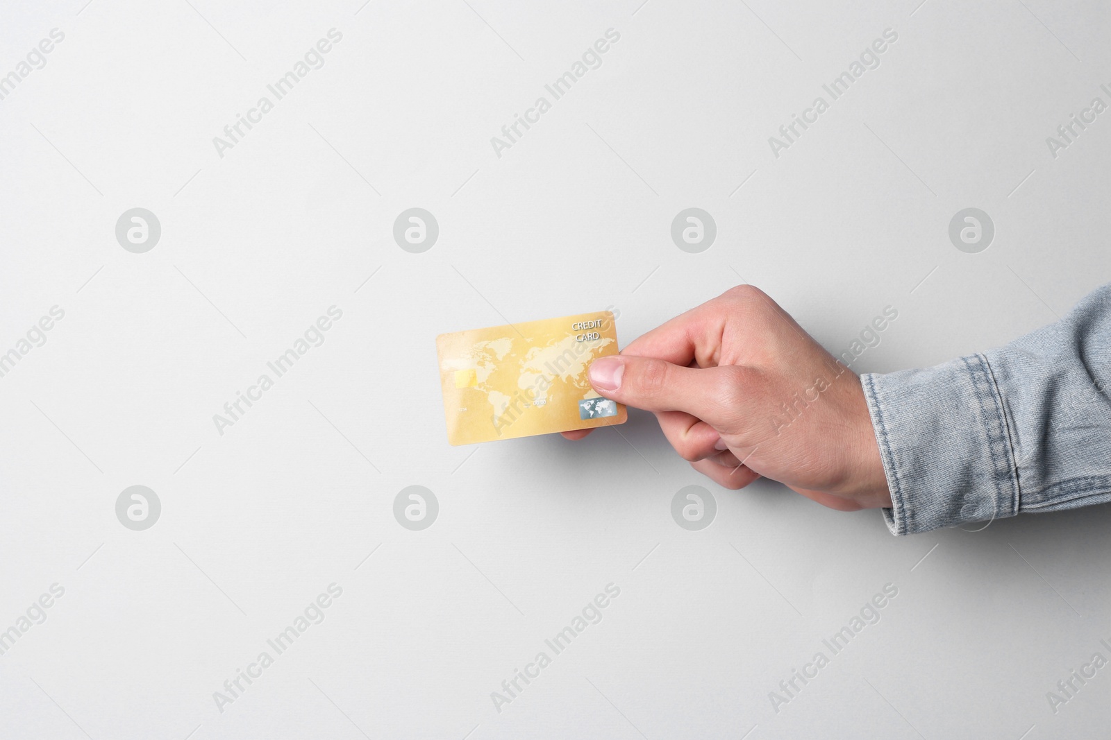 Photo of Man holding credit card on light grey background, closeup